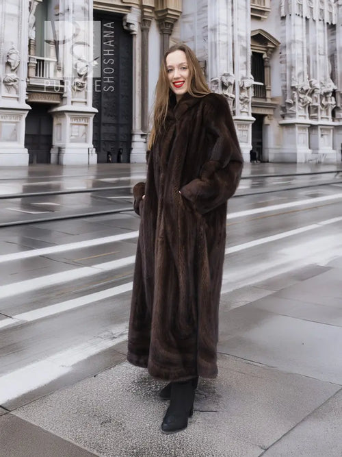 Long dark brown mink fur coat with hooded collar and plush texture, full-length view