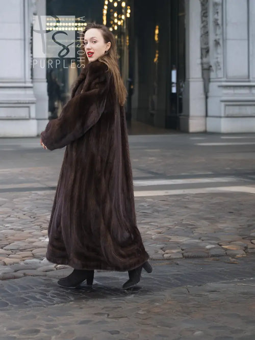 Long dark brown mink fur coat with plush texture, standing profile view