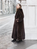 Long dark brown mink fur coat with hooded neckline, three-quarter side view