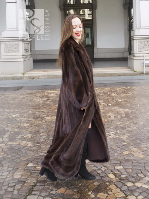 Long dark brown mink fur coat with open front and long hem, walking pose