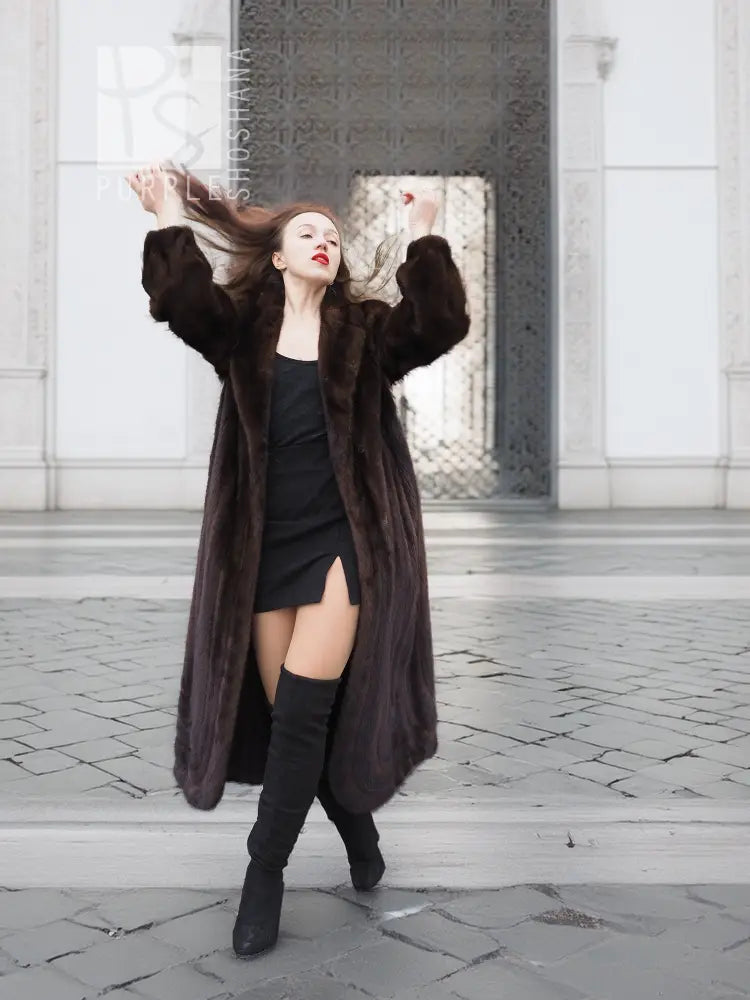 Dark brown mink fur coat with hood, open front showing black dress and slit