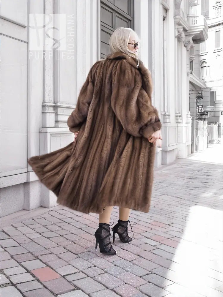 Dark brown mink fur coat with hood in side back view, long flared hem