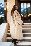 Cream faux-fur full-length coat with notched collar and long sleeves, three-quarter view.