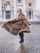 Long mink fur coat with swing shape and button front, shown from the side in espresso brown.