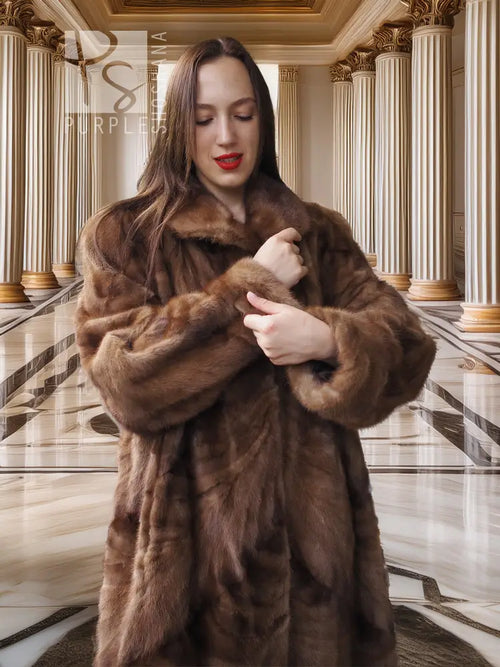 Long mink fur coat with plush texture in espresso brown, shown with clasped button at chest.