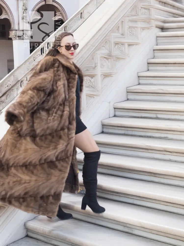 Long mink section coat in brown with wide collar and button front; three-quarter view