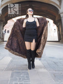 Long mink fur swing coat in espresso brown worn over a black dress and tall boots.