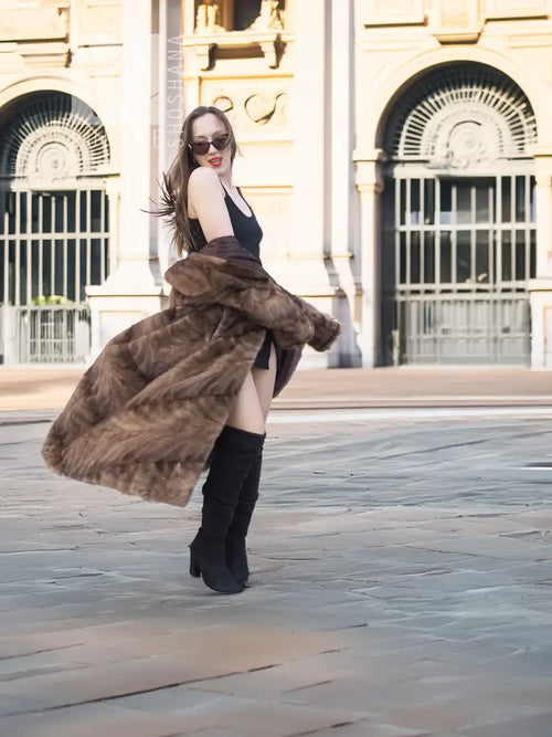 Long mink section coat in brown with wide collar and swing hem; three-quarter view