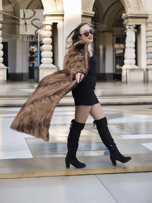 Long mink section coat in brown with wide collar and button front; side pose