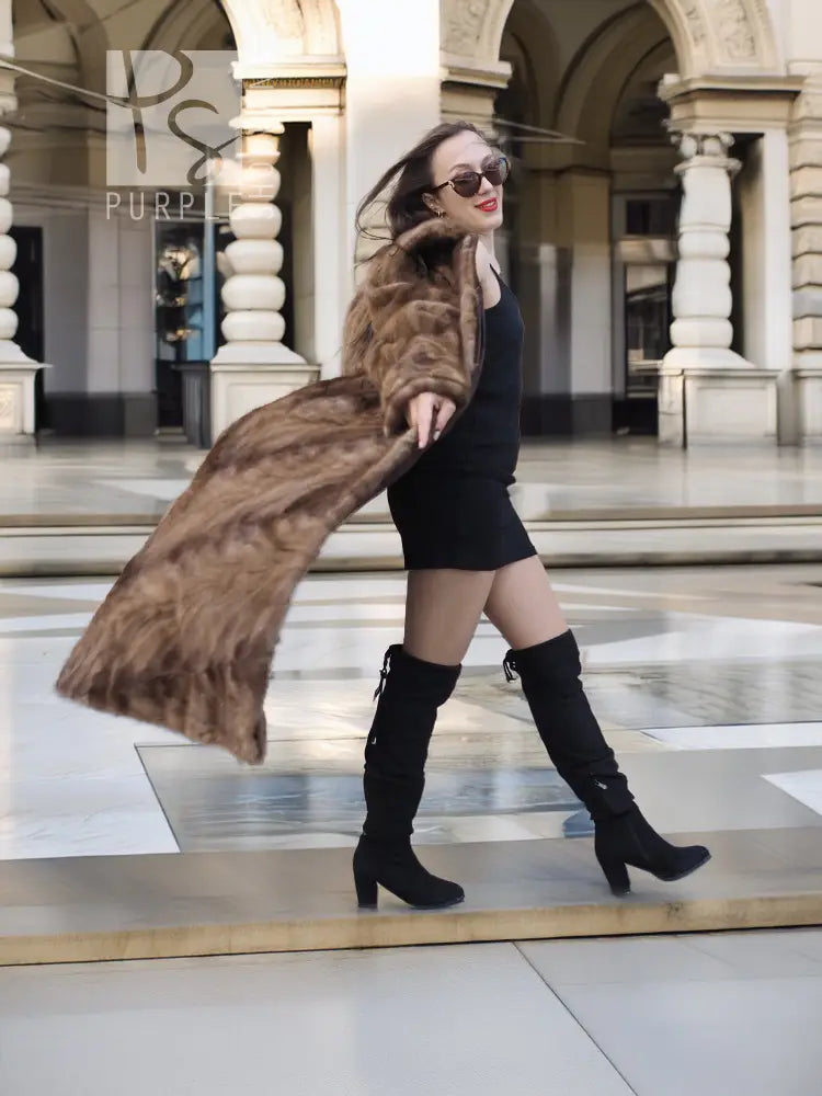Long mink section coat in brown with wide collar and button front; side pose