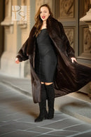 Dark fur coat worn open over a fitted dress; long sleeves and oversized collar