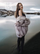 Fox fur coat with voluminous sculpted collar, light gray fur texture, worn over black.