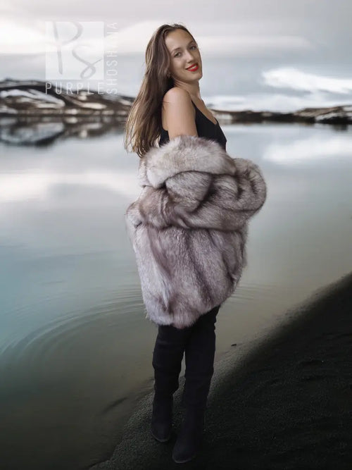Fox fur coat with voluminous sculpted collar, light gray fur texture, worn over black.