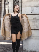 Beige mink fur cape-style jacket with open front over a black slip dress.