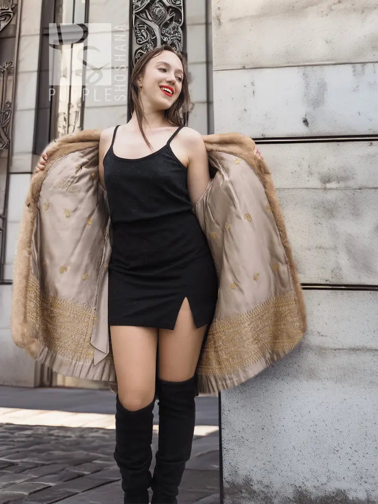 Beige mink fur cape-style jacket with open front over a black slip dress.