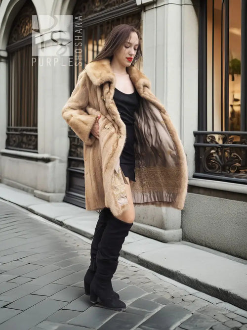 Beige mink fur coat with plush collar, open front over a black dress and boots.