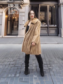Beige mink fur coat with plush collar, worn over a black dress and tall boots.
