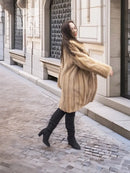 Beige mink fur coat with stand collar and button front; side view with sleeves extending.