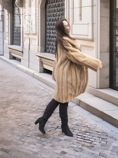 Beige mink fur coat with stand collar and button front; side view with sleeves extending.