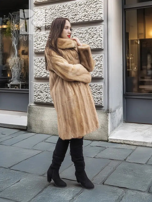 Beige mink fur coat with wide fur collar, worn over a black dress and tall boots.