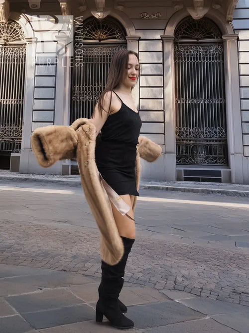Beige mink fur coat with long sleeves and open front over a black slip dress.