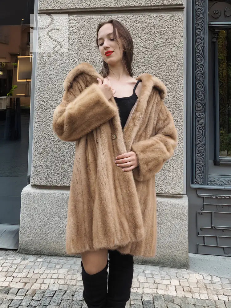 Beige mink fur coat with short sleeves and wide fur collar over a black dress.