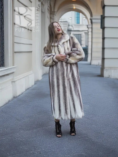 Long hooded mink fur coat with cross-stripe pattern, arms folded front view.