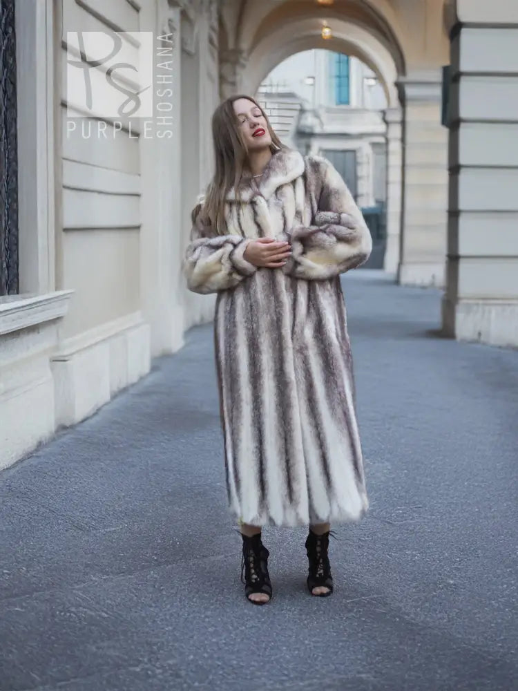 Long hooded mink fur coat with cross-stripe pattern, arms folded front view.