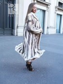 Side view of a long hooded mink fur coat with cross-stripe pattern and flared skirt.