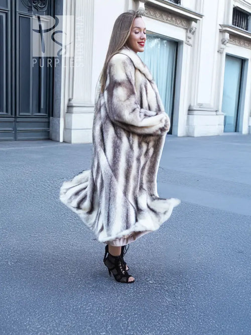 Side view of a long hooded mink fur coat with cross-stripe pattern and flared skirt.