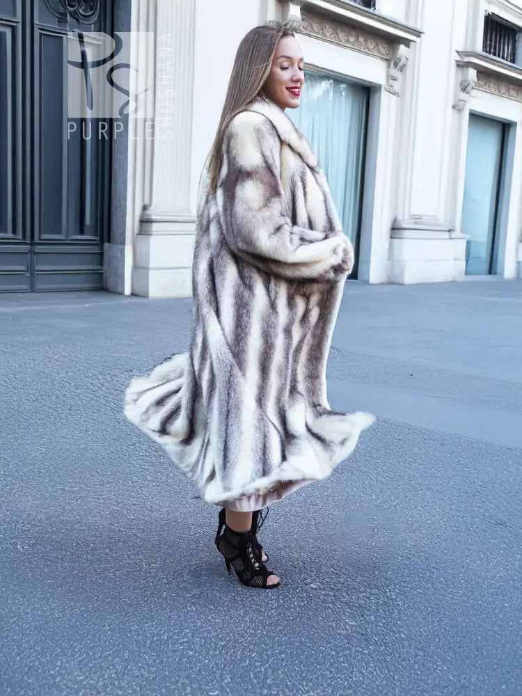 Side view of a long hooded mink fur coat with cross-stripe pattern and flared skirt.