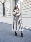 Hooded long mink fur coat with cross-stripe pattern, front view with relaxed arms.