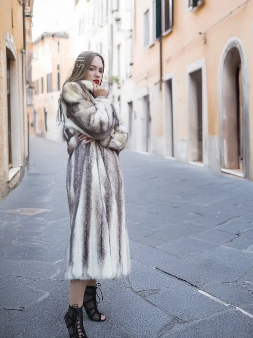 Mink fur hooded coat with full-length skirt, standing in a narrow street setting