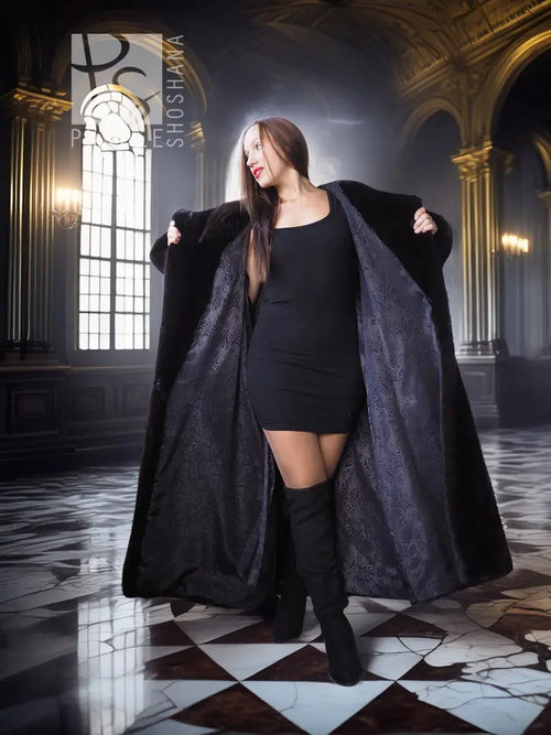 Black long hooded fur coat with open front and plush sleeves, styled over a short black dress