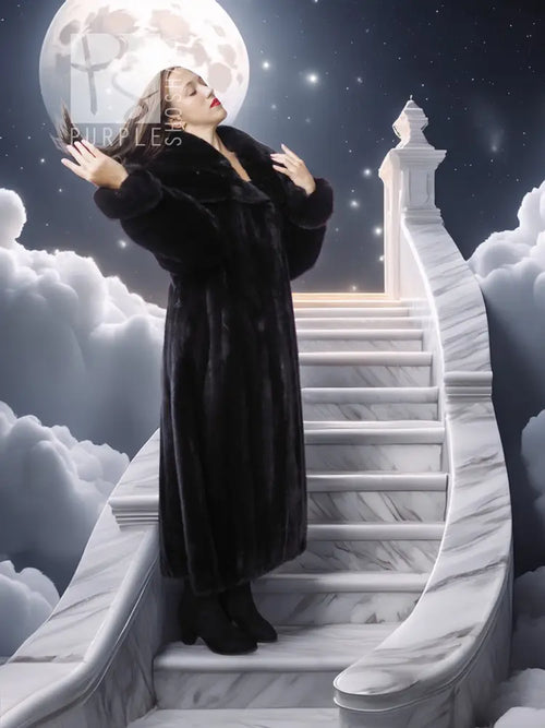 Black hooded long mink coat with silk lining; model holds hood back with both hands.