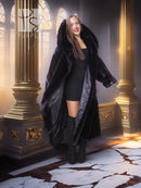 Black long hooded fur coat with open front and broad sleeves, styled over a short black dress