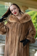 Front close-up: tan mink fur hooded coat with plush collar; black gloves