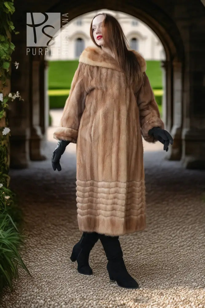Tan mink fur long coat with hood and ribbed hem, seen full length with black boots