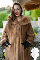 Tan mink fur coat with wide hood and full sleeves; black gloves and boots