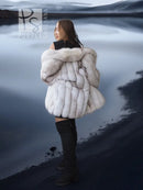 Side view of white faux fur coat with shawl collar, voluminous shoulders and sleeves.