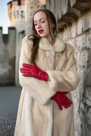 Ivory mink coat close-up: fur collar and textured sleeves, red gloves