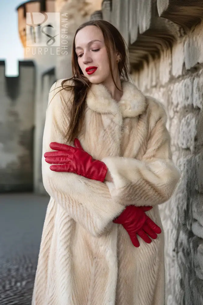 Ivory mink coat close-up: fur collar and textured sleeves, red gloves