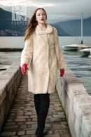 Ivory mink coat with textured front and full-length cut, red gloves