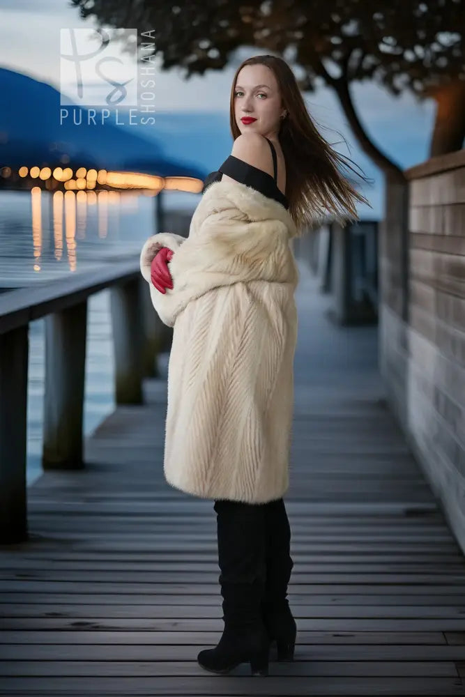 Ivory mink coat in profile with thick collar and red gloves