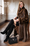 Women’s dark brown mink coat with hood, draped sleeves, and button front while seated.