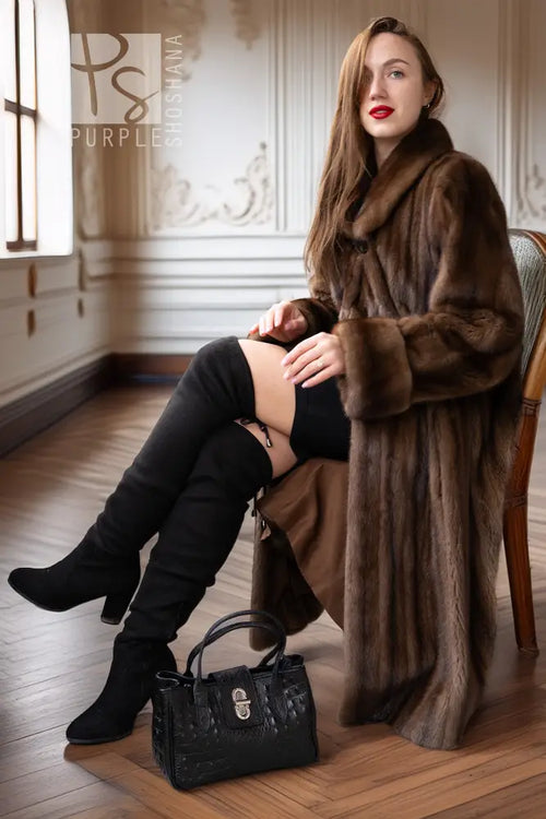 Women’s dark brown mink coat with hood, draped sleeves, and button front while seated.
