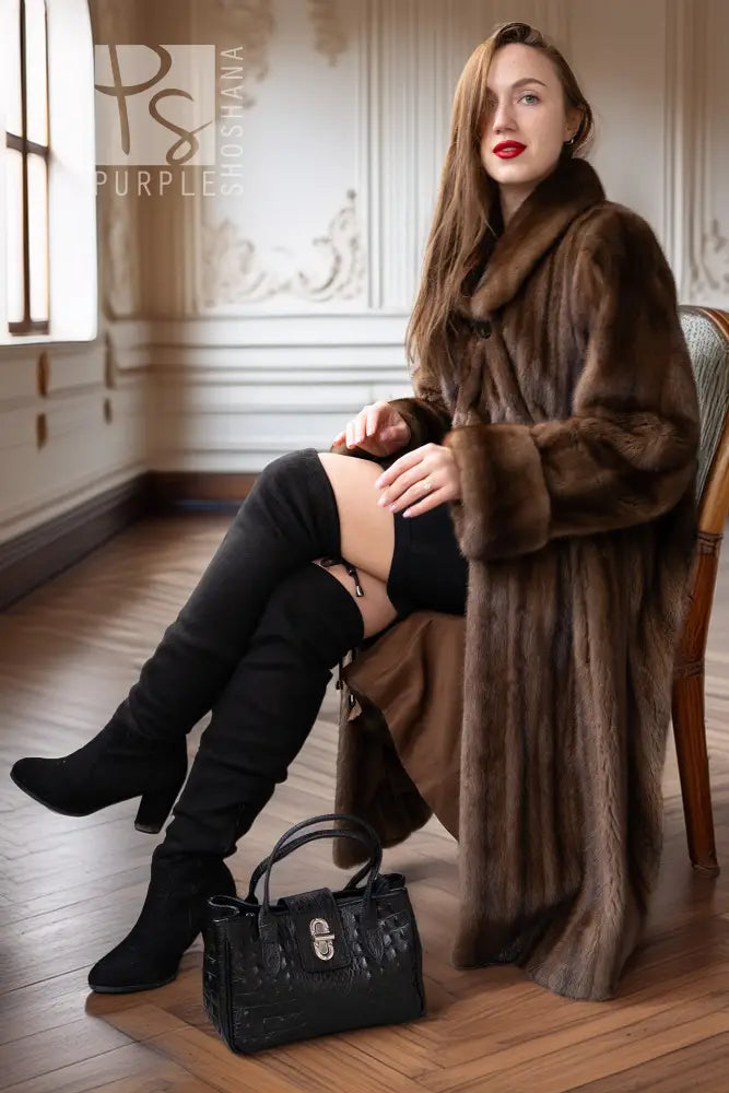 Women’s dark brown mink coat with hood, draped sleeves, and button front while seated.