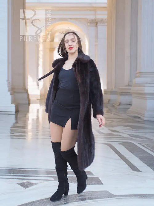 Long mink fur coat with tie belt and wide collar, open front showing dress and boots