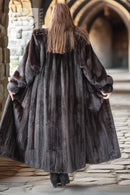 Back view of a long black mink fur coat with full sleeves and straight hem