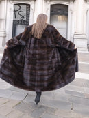 Back view of dark brown mink fur coat with horizontal stripe pattern and wide hem